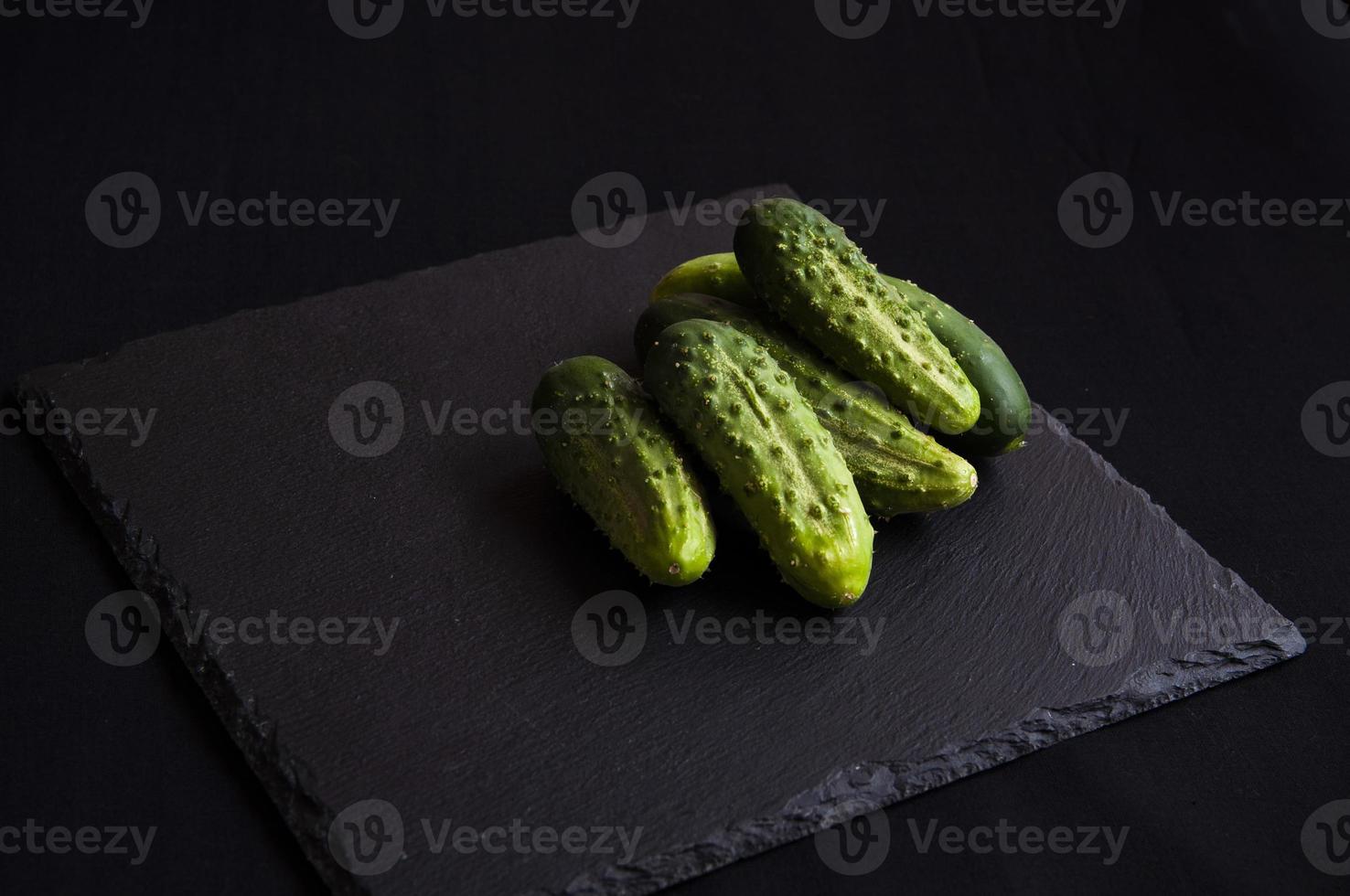 natürliche frische grüne Gurken aus dem heimischen Garten auf schwarzem Hintergrund foto