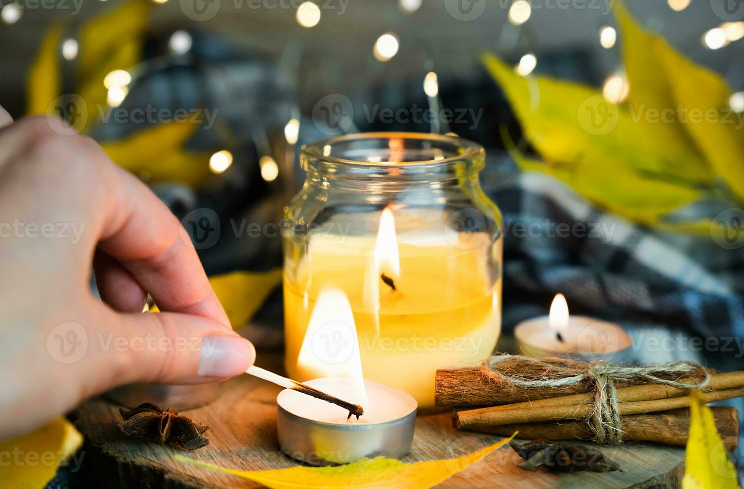 ein Frau Hand Beleuchtung ein Kerze mit ein passen. warm herbstlich Komposition. selektiv Fokus. foto