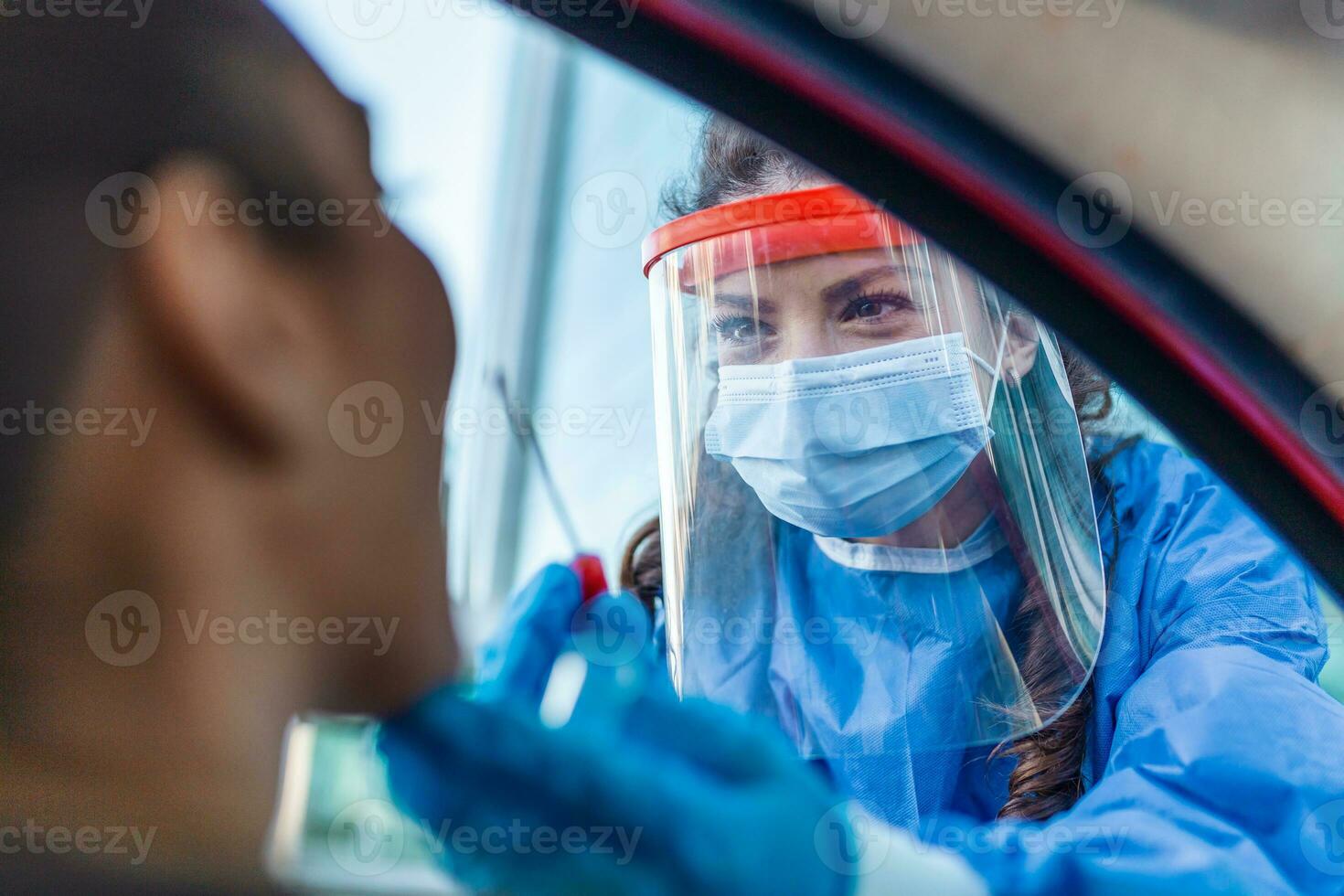 Arzt oder Krankenschwester tragen pp, n95 Maske, Gesicht Schild und persönlich schützend Kleid Stehen neben das Auto Straße Screening zum covid-19 Virus, Nasal- Tupfer prüfen. foto