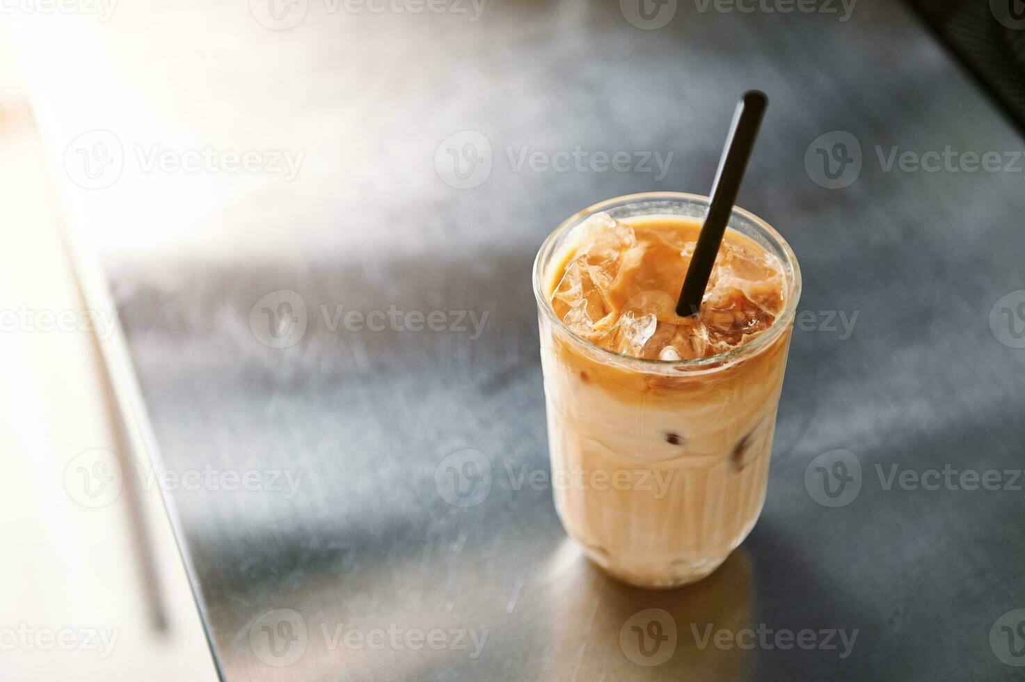 hoch Winkel Aussicht von ein vereist Kaffee Latté mit Stroh auf ein Stahl Zähler oben im Kaffee Haus. foto