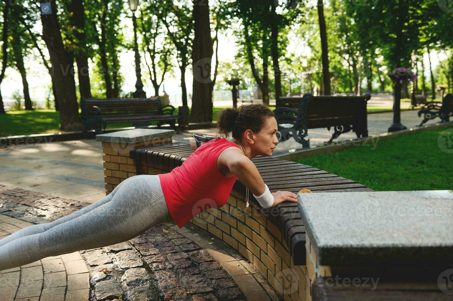 entschlossen spanisch Frau genießen Morgen funktional Kreuz trainieren im Stadt Park auf ein schön heiß sonnig Sommer- Tag foto