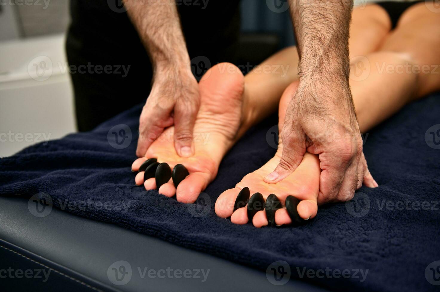 Nahansicht von Masseur geben ein heiß Stein ayurvedisch Massage zu Frau Füße. heiß Stein Massage Therapie foto