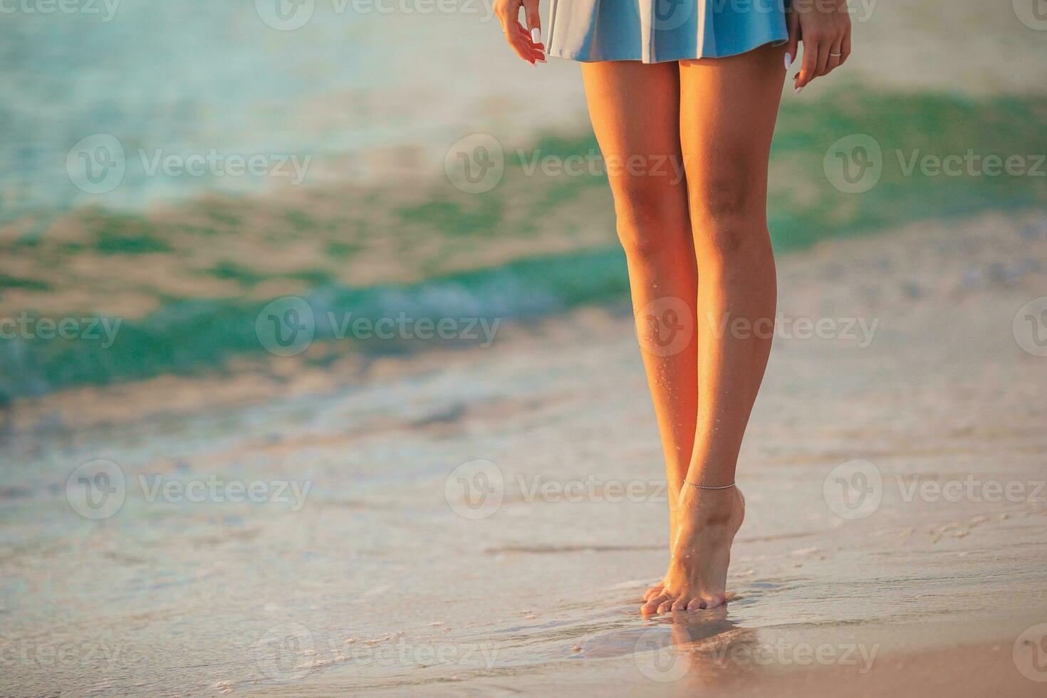 weibliche beine am strand nahaufnahme. Mädchen, das am Strand spazieren geht foto