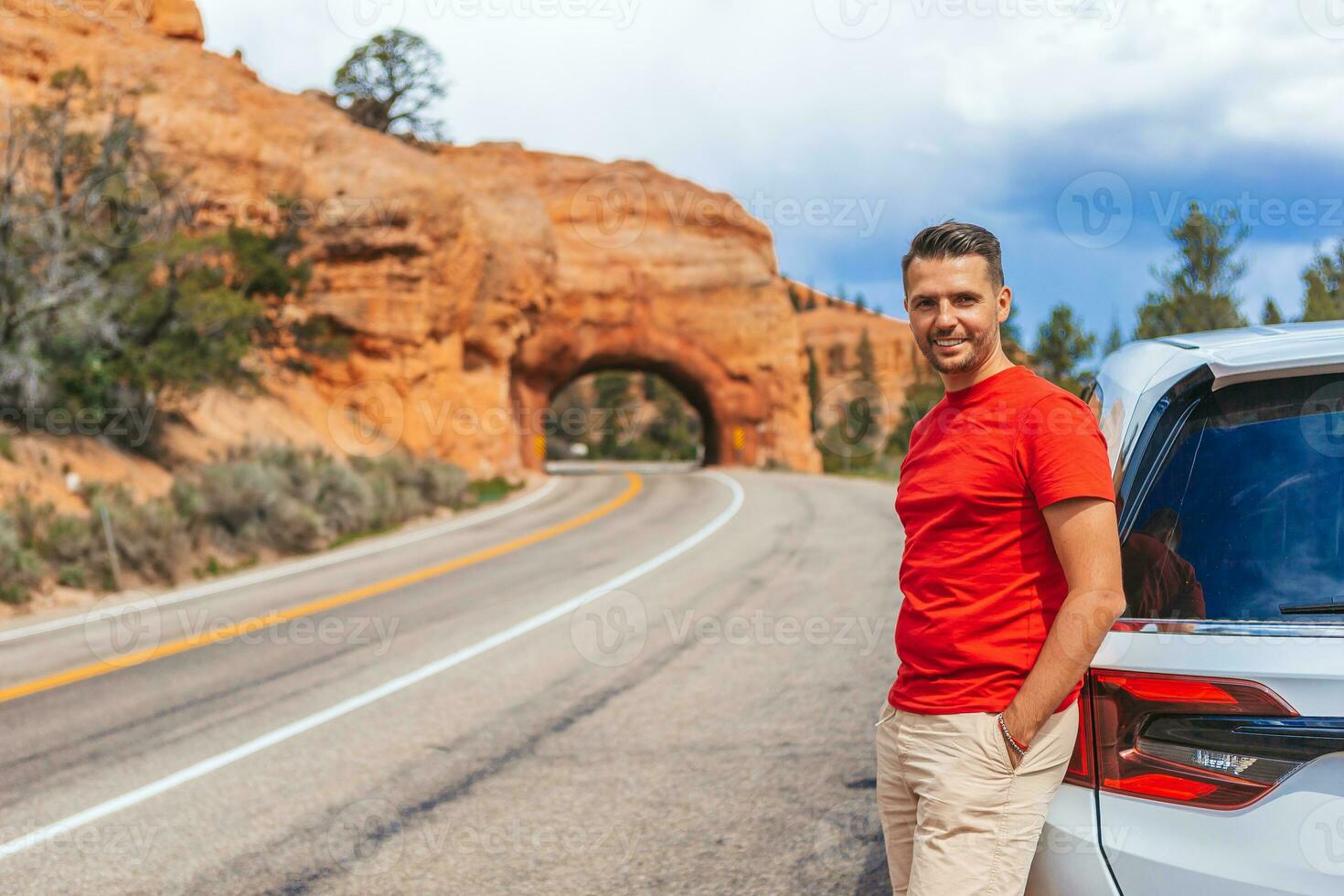 jung kaukasisch Mann im Hintergrund von natürlich Stein Bogen Brücke im das rot Schlucht National Park im Utah, USA foto