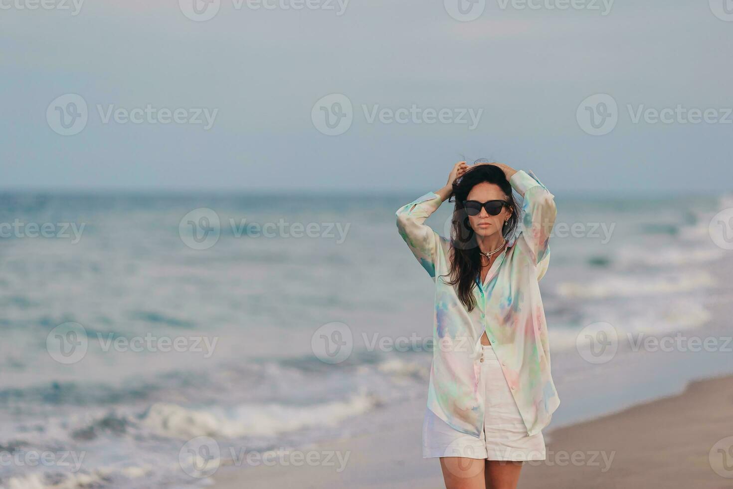 jung glücklich Frau auf das Strand genießen ihr Sommer- Urlaub. Frau Gehen entlang das Meer im Abend. foto