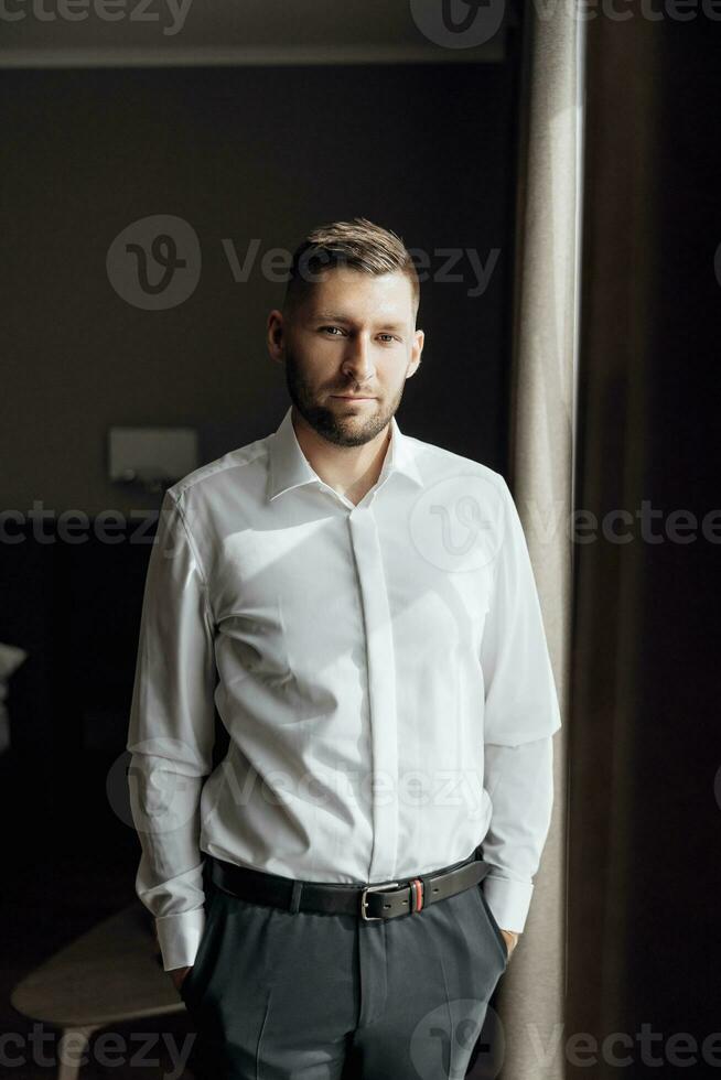 das stilvoll Bräutigam Kleider, bereitet vor zum das Hochzeit Zeremonie. groß Porträt. wunderbar Innere im das Morgen Licht. das Bräutigam Morgen foto