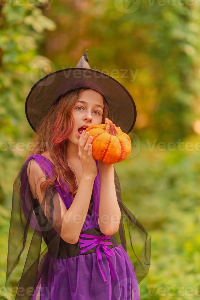 junges Mädchen im Halloween-Kostüm mit Kürbis foto