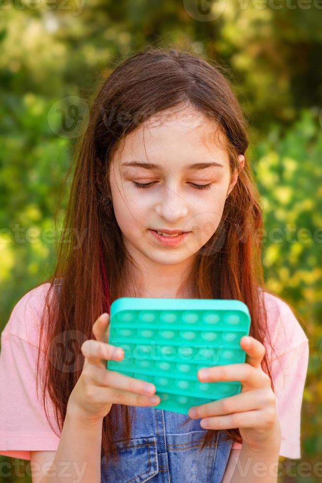 Porträtmädchen mit modernem Pop-it-Spielzeug foto