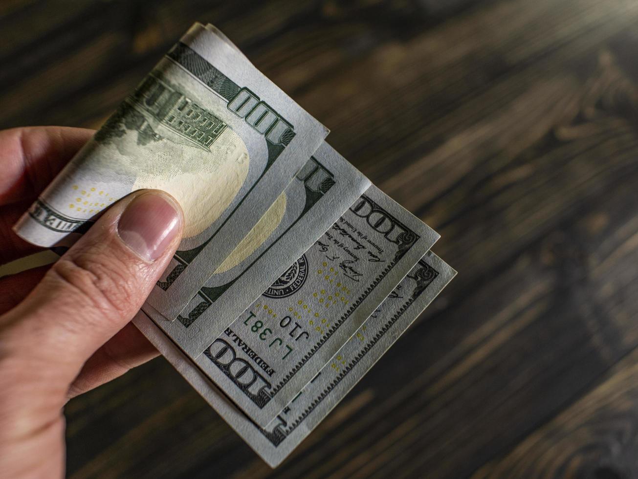 männliche Hand hält zwei Banknoten von hundert Dollar foto