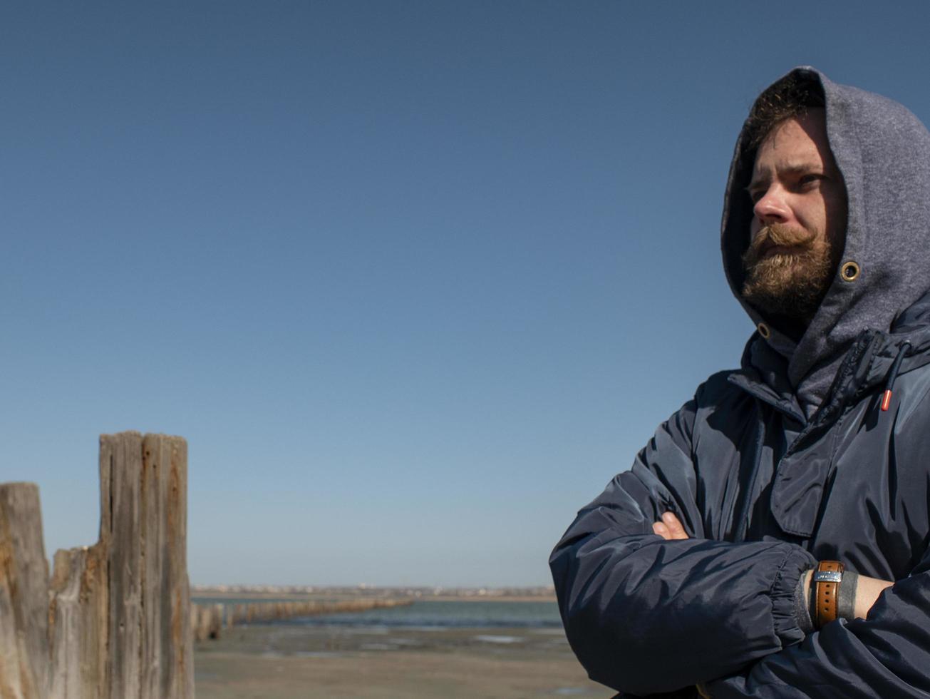 Mann Hipster mit Bart und Schnurrbart in der Kapuze gegen den blauen Himmel foto