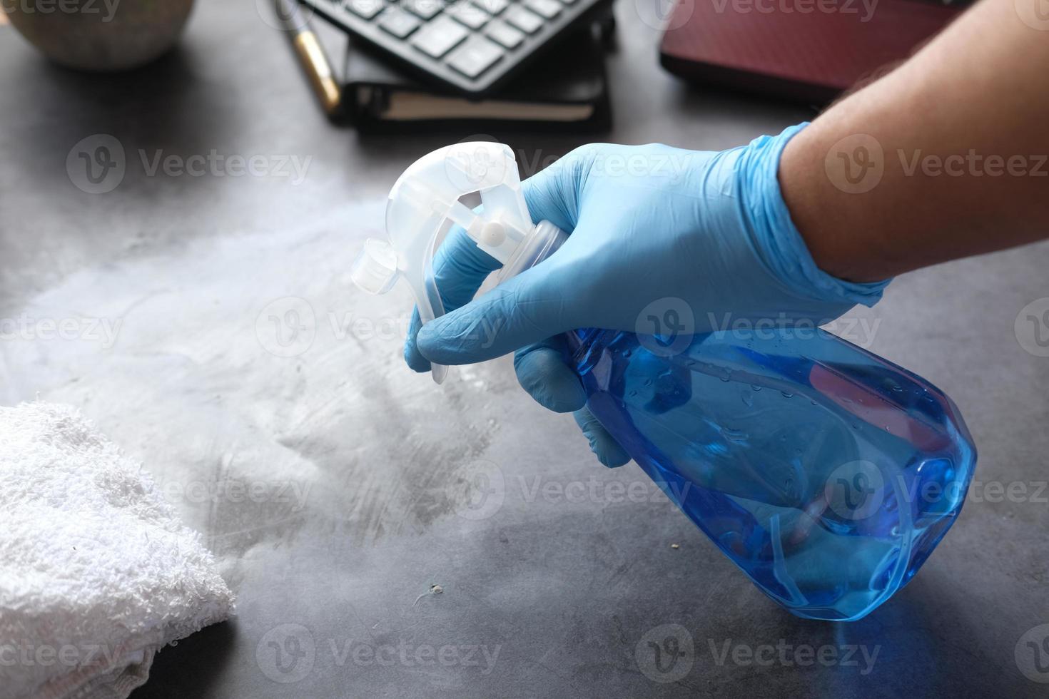 Hand in blauen Gummihandschuhen mit Sprühflaschen-Reinigungstisch foto