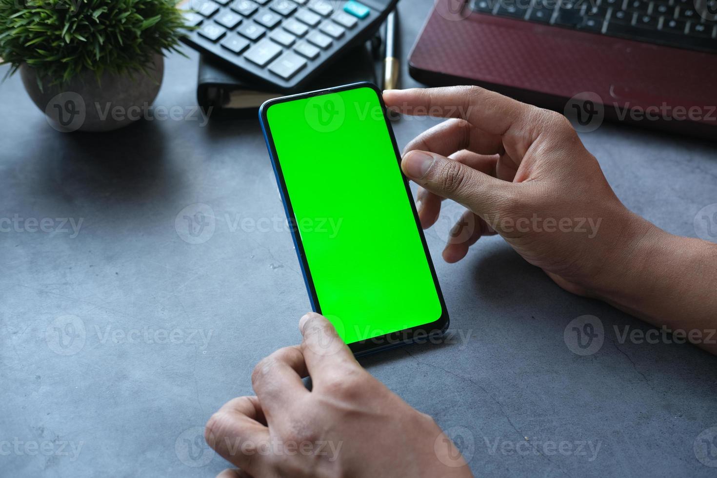 Rückansicht der Hand des Mannes mit Smartphone auf dem Schreibtisch foto