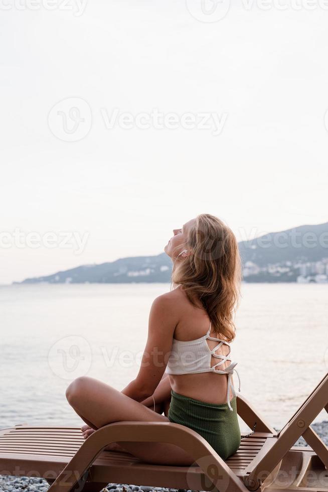 Frau sitzt auf der Sonnenliege, hört Musik und tanzt foto