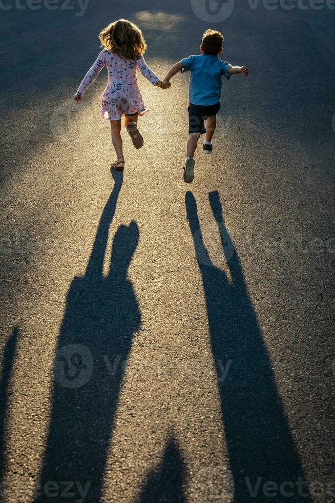 Rückseite Aussicht von Geschwister halten Hände und Laufen auf Straße foto