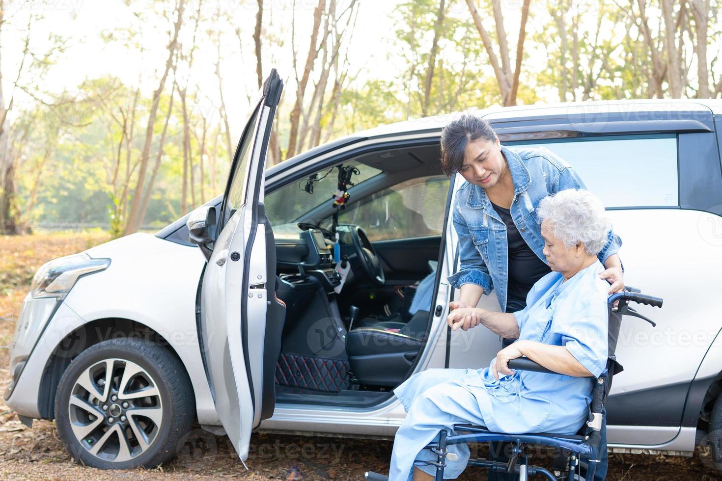 Helfen Sie einer asiatischen Seniorin, die im Rollstuhl sitzt, zu ihrem Auto zu gelangen foto