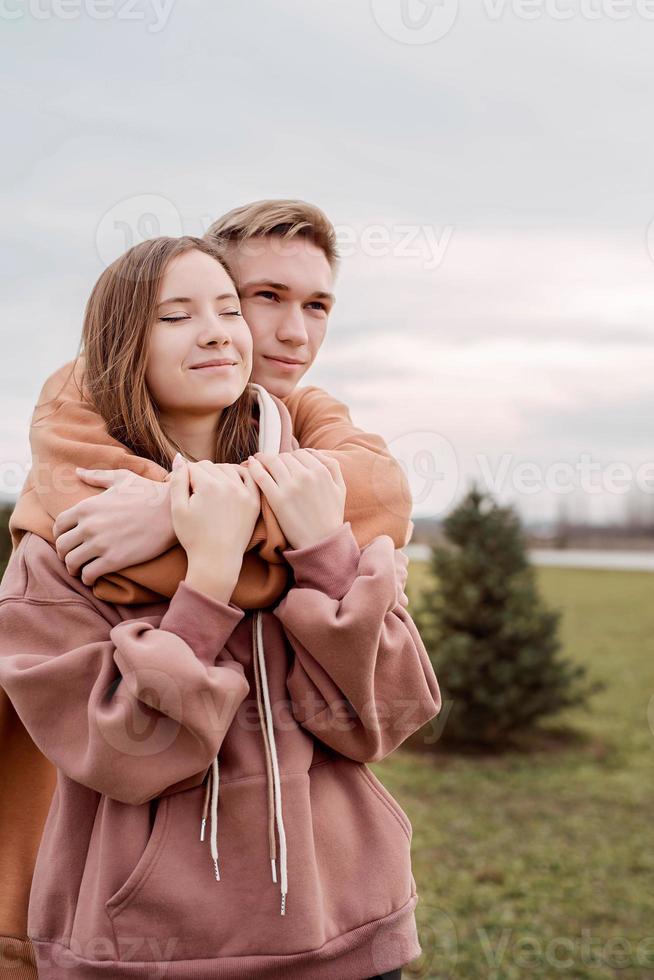 junges Liebespaar umarmt sich draußen im Park foto