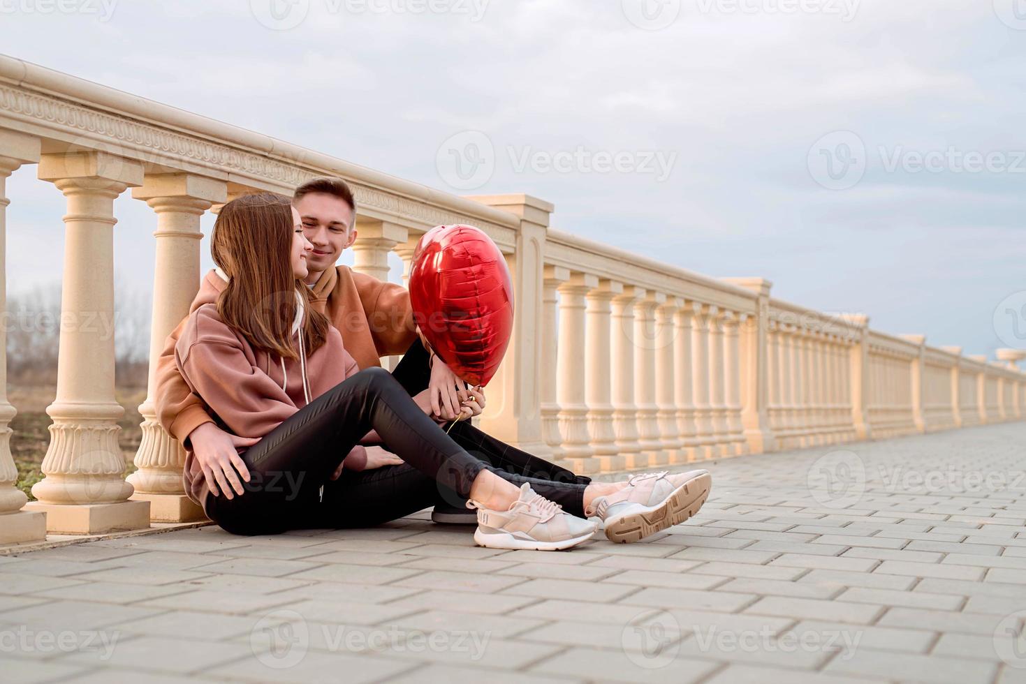 Paare, die sich draußen im Park mit Luftballons umarmen foto