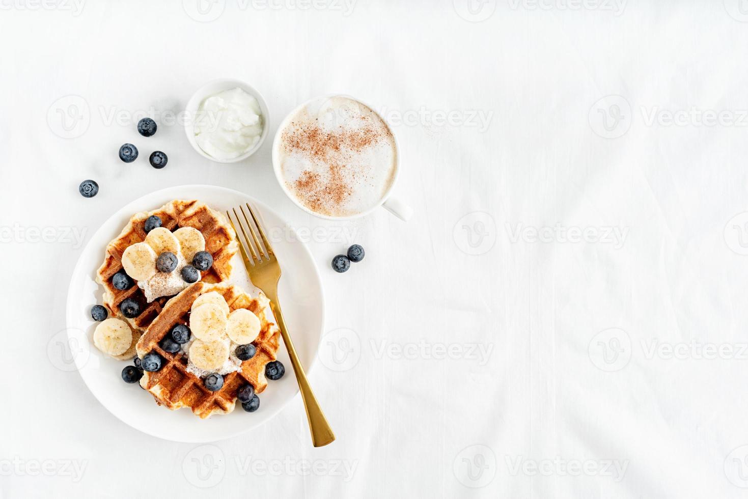 Draufsicht auf frisch zubereitete Waffeln mit Blaubeeren, Banane und Joghurt and foto