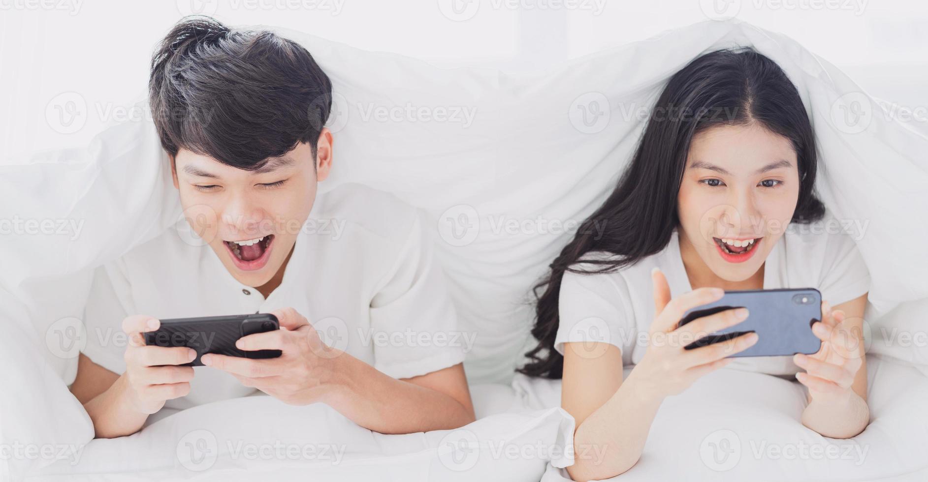 junges Paar mit Telefon im Bett mit fröhlichen Ausdrücken expression foto