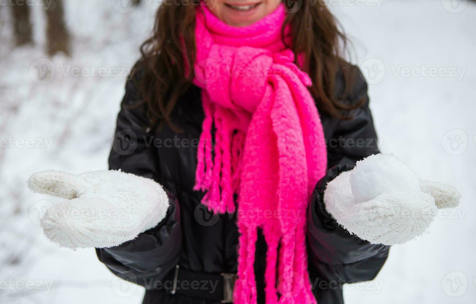 jung Frau halten natürlich Sanft Weiß Schnee im ihr Hände zu machen ein Schneeball, lächelnd auf ein kalt Winter Tag im das Wald, draußen. foto