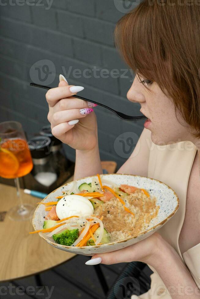 jung Frau mit Teller und Gabel genießen das Geschmack von Andenhirse und Lachs Salat foto