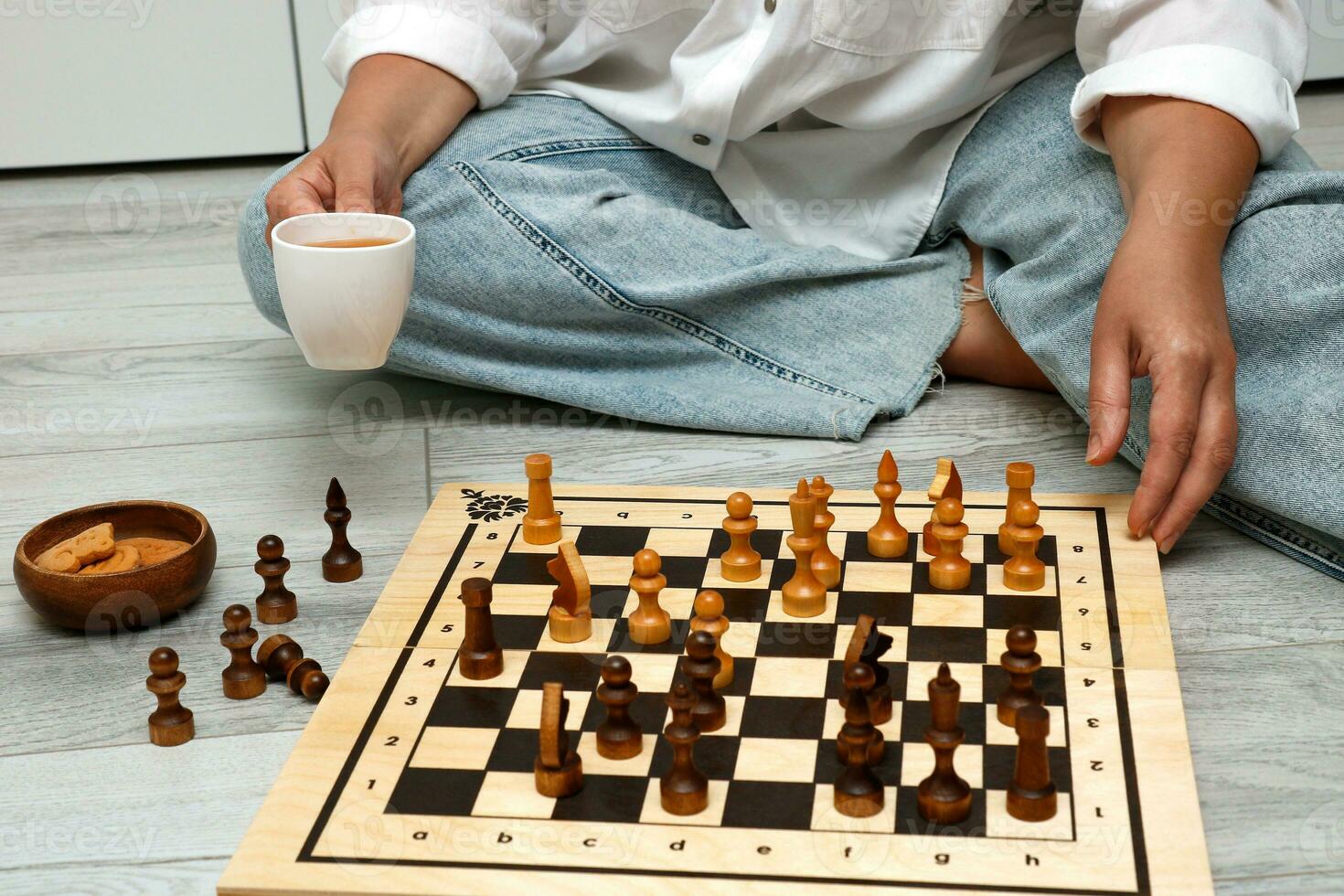 Frau mit ein Tasse von Tee spielen Schach beim heim. foto