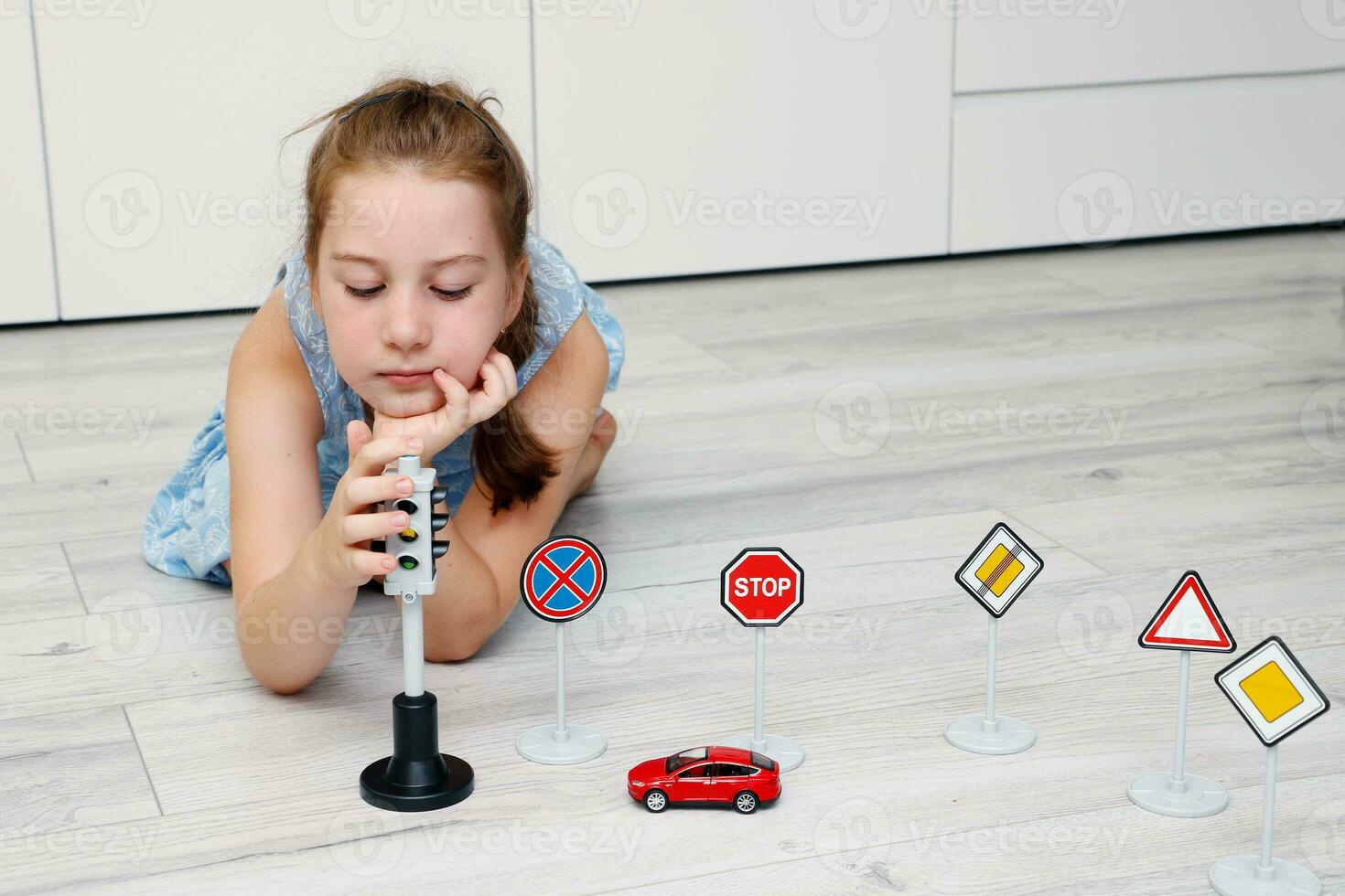 süß wenig Mädchen spielen beim Zuhause auf das Fußboden mit ein Schreibmaschine, Straße Zeichen und der Verkehr Beleuchtung foto