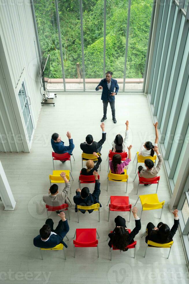oben Aussicht von ein Gruppe von Geschäft Menschen Sitzung und Hören zu ein Präsentation im ein Konferenz Halle foto