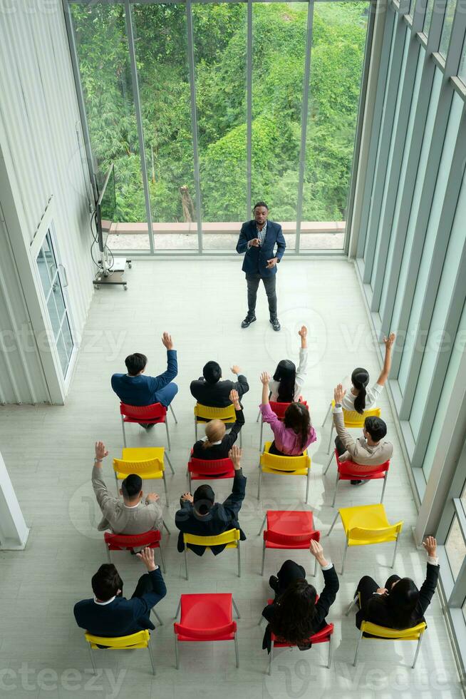 oben Aussicht von ein Gruppe von Geschäft Menschen Sitzung und Hören zu ein Präsentation im ein Konferenz Halle foto