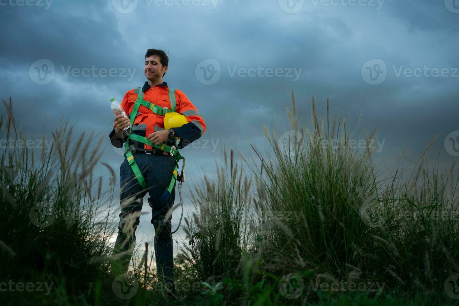Porträt von ein jung Mann Arbeiten im Wind Turbine Feld, tragen ein Sicherheit Weste, das Konzept von entspannen Zeit nach Arbeit foto
