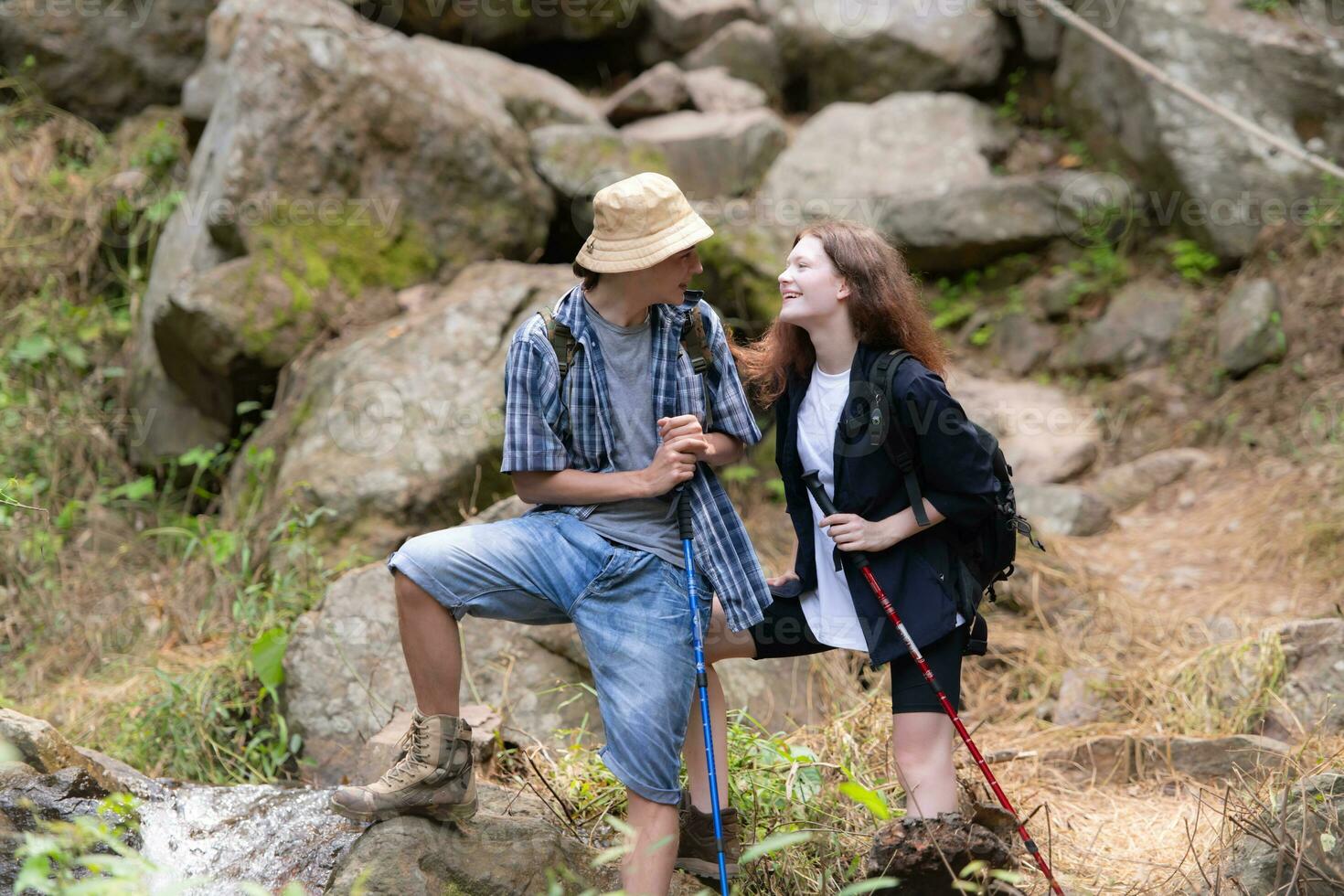 jung Paar Wandern im das Wald mit Rucksäcke und Trekking Stangen foto