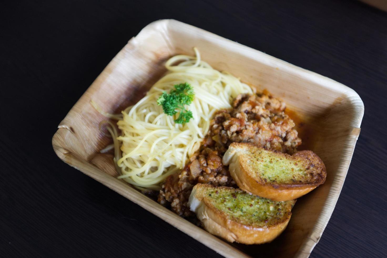 Spaghetti-Schweinefleisch-Tomatensauce mit einer Scheibe Knoblauchbaguette foto