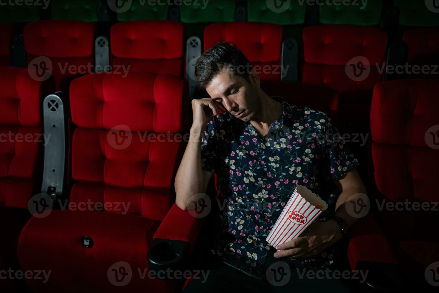 Mann Stürze schlafend während Aufpassen Film im Kino und Popcorn im Hand, Film fehlt interessant und langweilig. foto