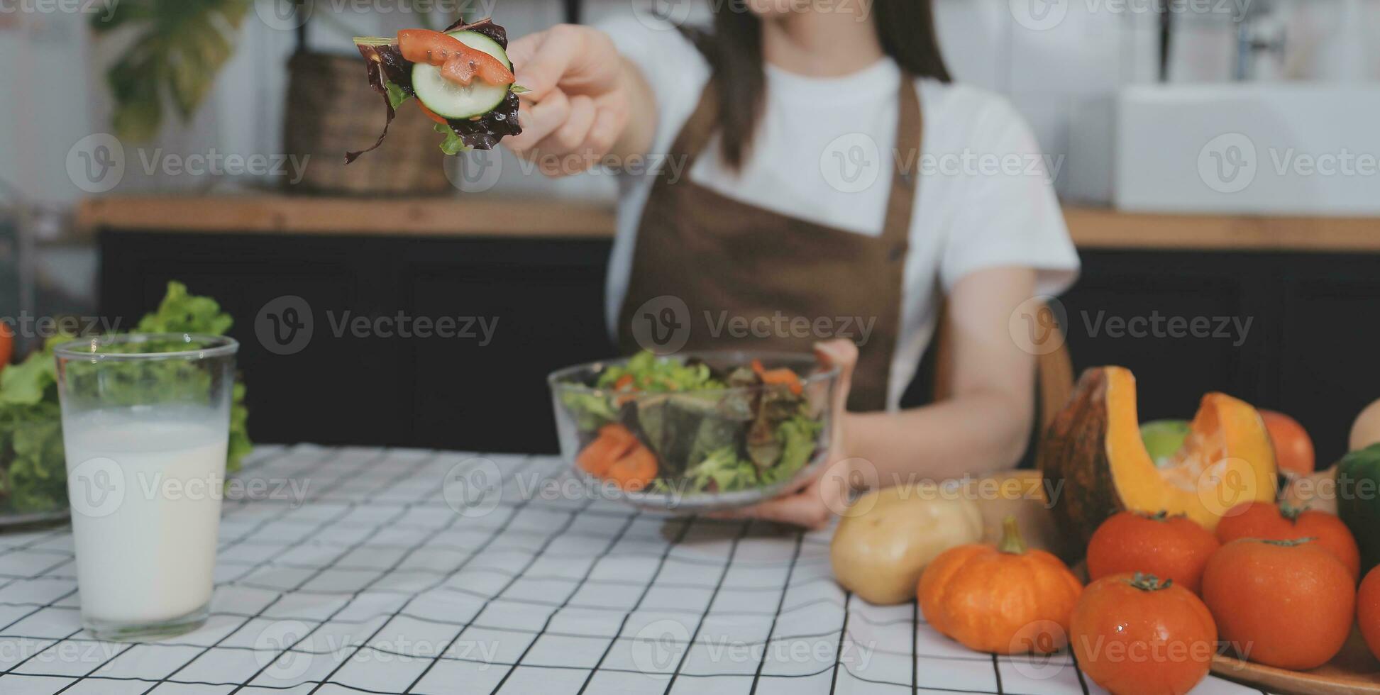 köstlich Obst und Gemüse auf ein Tabelle und Frau Kochen. Hausfrau ist Schneiden Grün Gurken auf ein hölzern Tafel zum Herstellung frisch Salat im das Küche. foto