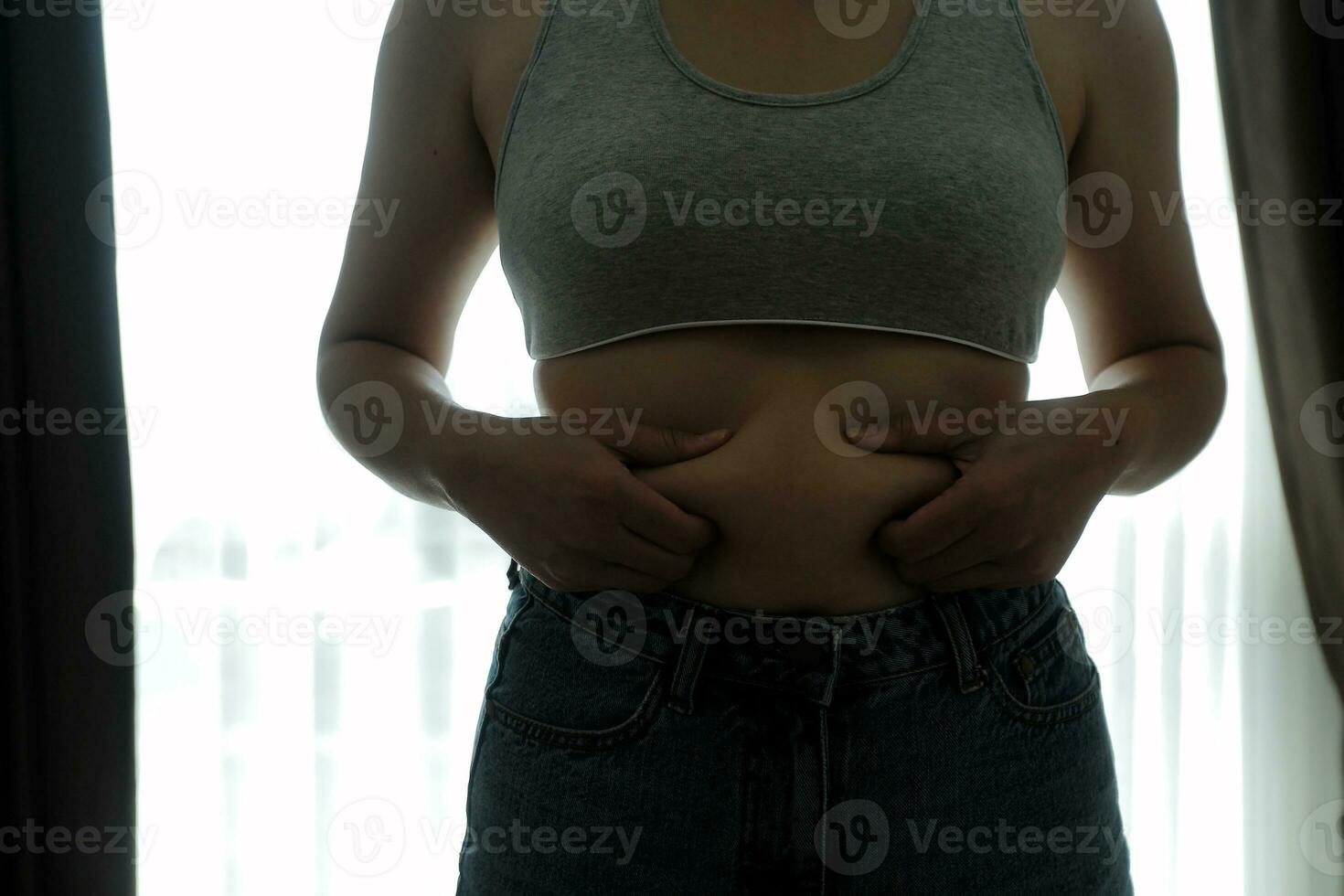 schließen oben von ein Bauch mit Narbe von Kaiserschnitt und Bauch fett. Damen Gesundheit. ein Frau gekleidet oben im Sportbekleidung demonstrieren ihr unvollkommen Körper nach ein Geburt mit Kindergarten auf das Hintergrund. foto