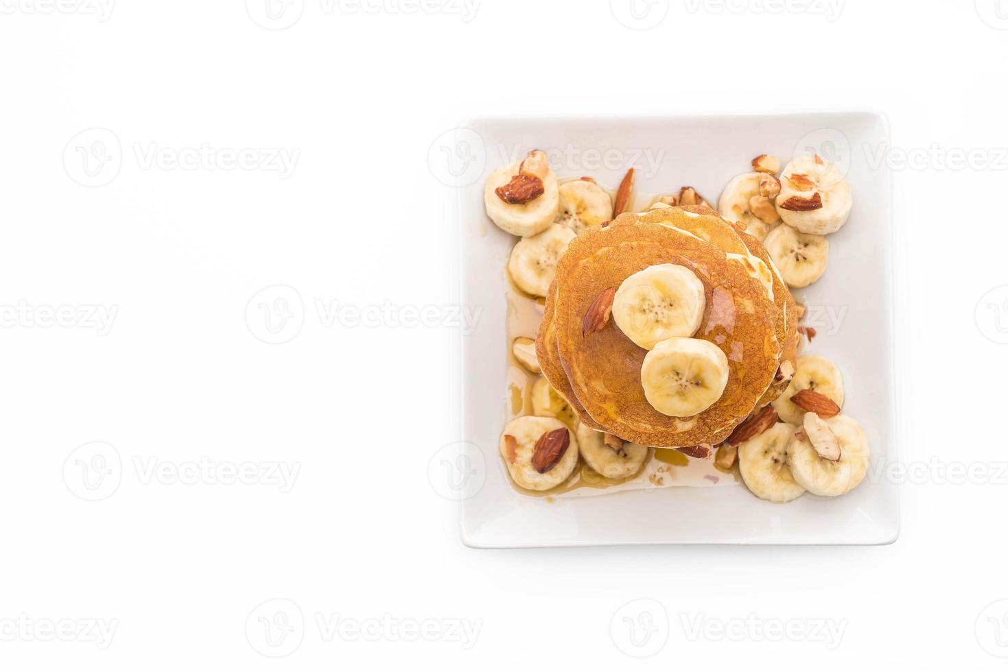 Mandel-Bananen-Pfannkuchen mit Honig auf weißem Hintergrund foto