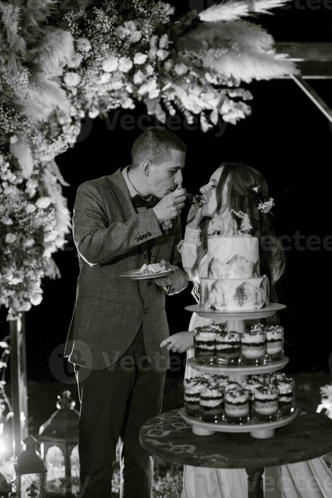 Jungvermählten schneiden glücklich die Hochzeitstorte an und probieren sie foto