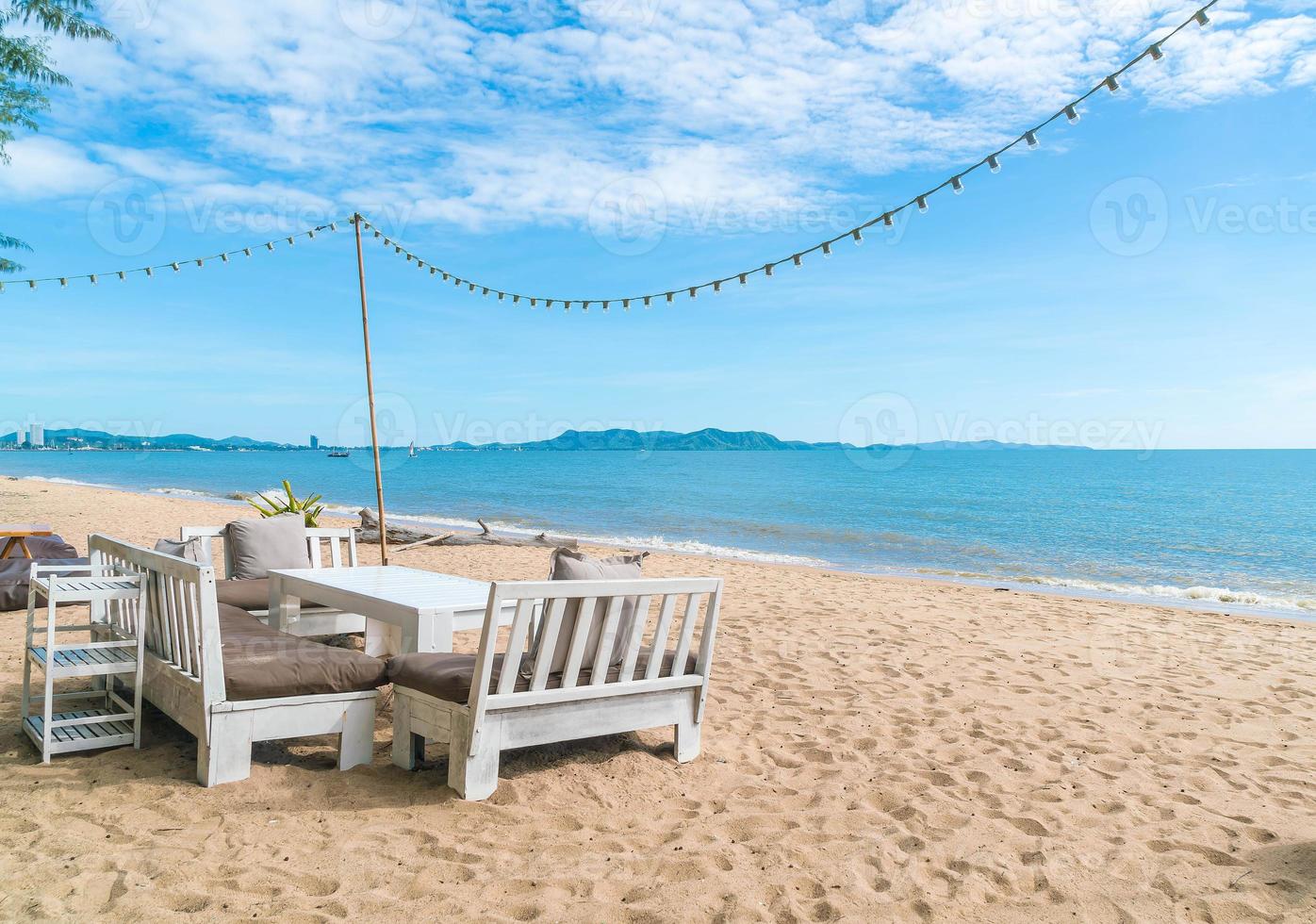 weiße Stühle und Tisch am Strand mit Blick auf das blaue Meer und den klaren Himmel foto