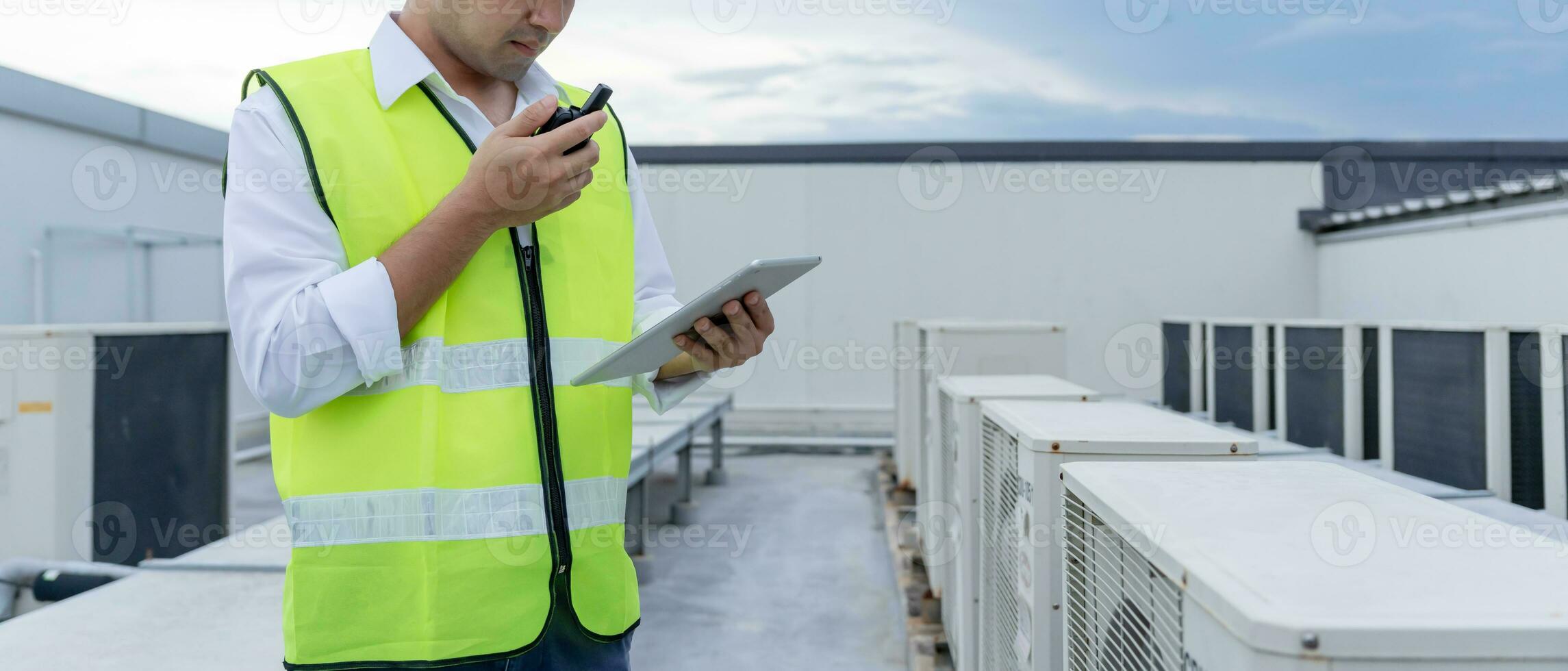 asiatisch Instandhaltung Ingenieur funktioniert auf das Dach von Fabrik. Auftragnehmer prüfen Kompressor System und Pläne Installation von Luft Bedingung Systeme im Konstruktion. Technologie, online, Handy, Mobiltelefon Anwendung. foto