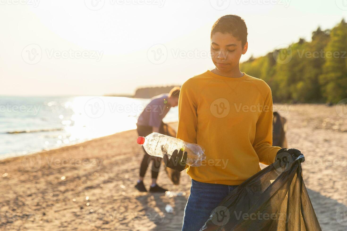 Erde Tag. Freiwillige Aktivisten sammelt Müll Reinigung von Strand Küsten Zone. Frau setzt Plastik Flasche Müll im Müll Tasche auf Ozean Ufer. Umwelt Erhaltung Küsten Zone Reinigung. foto