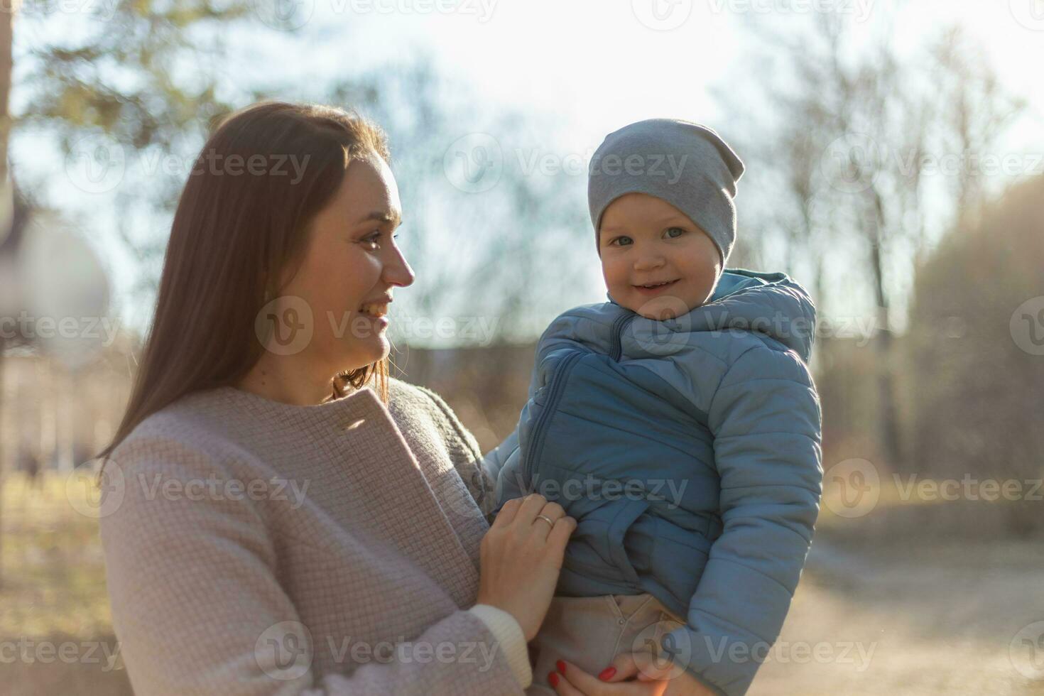 glücklich Familie draussen. Mutter Umarmen ihr Kind draussen. Mama Heben im Luft wenig Kleinkind Kind Sohn. Frau und wenig Baby Junge ruhen Gehen im Park. Mutter Umarmungen Baby mit Liebe Pflege. foto