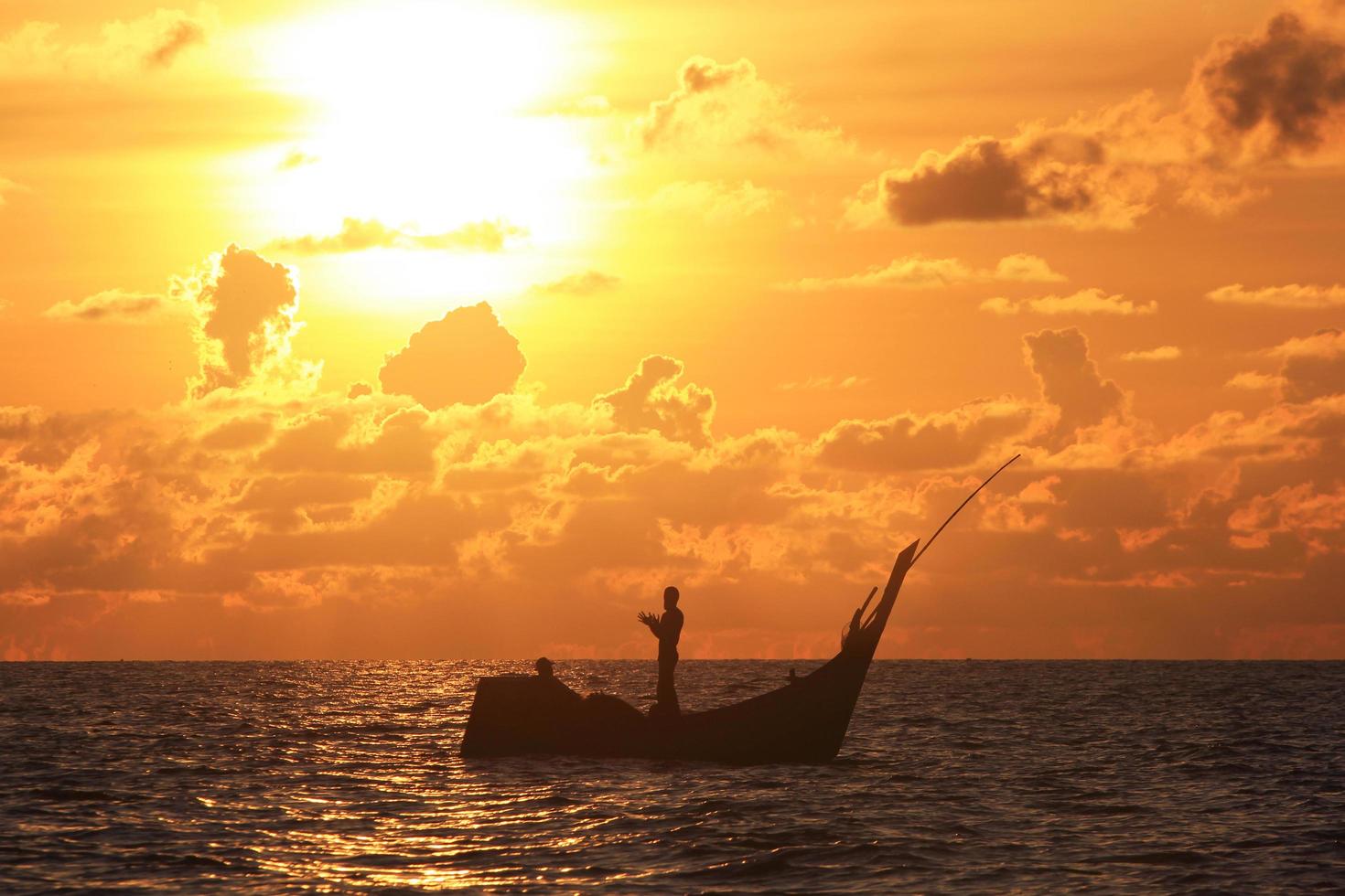 ein Fischer betet mit einem sehr schönen Sonnenuntergangshintergrund foto