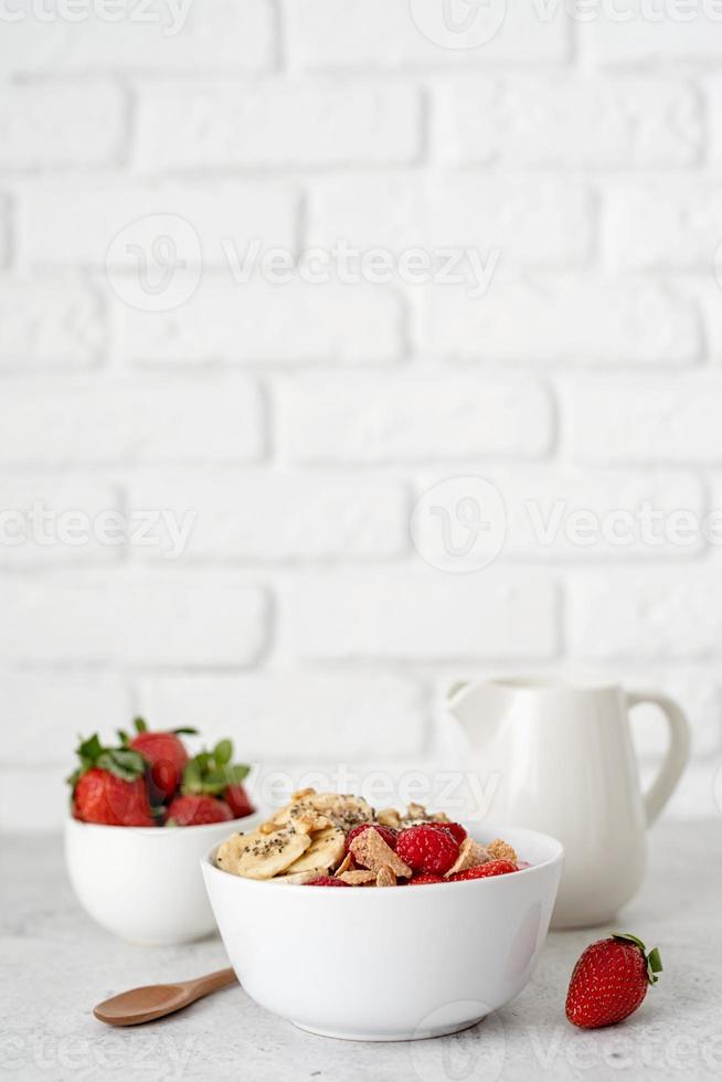 Müsli, frische Erdbeeren und Milch in einer Schüssel foto