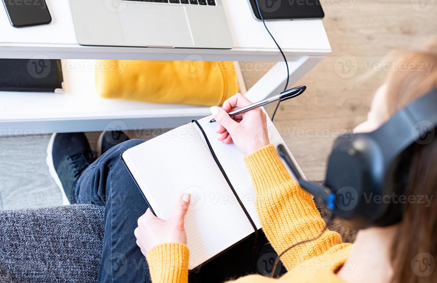 junge lächelnde Frau in schwarzen Kopfhörern, die online mit Laptop studiert? foto