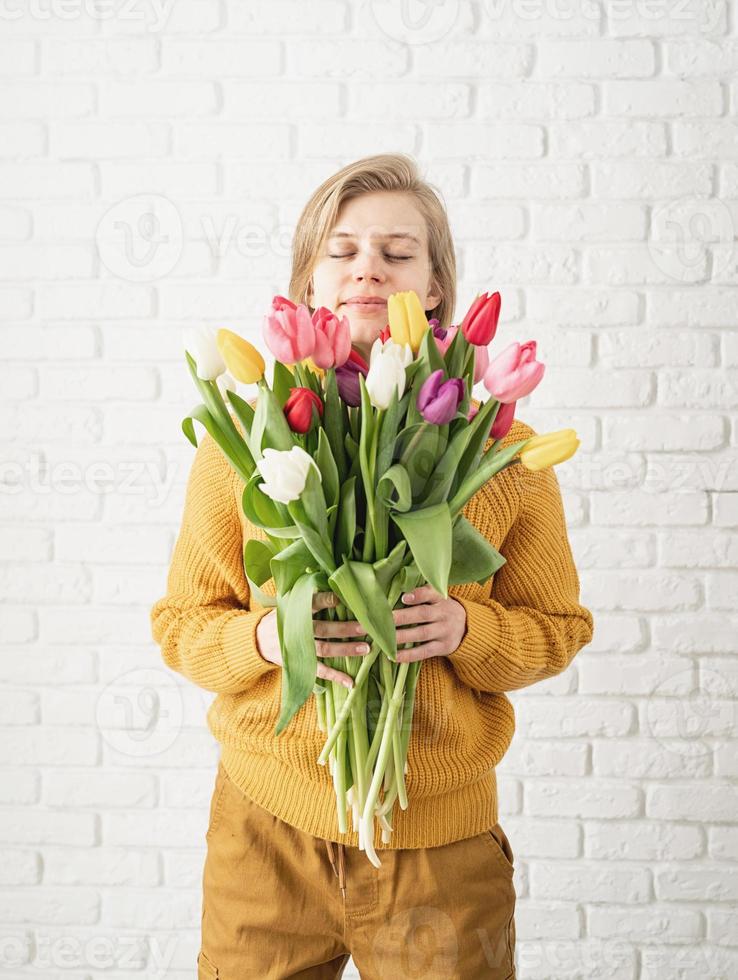 glückliche schöne frau in gelber kleidung, die einen tulpenstrauß hält foto