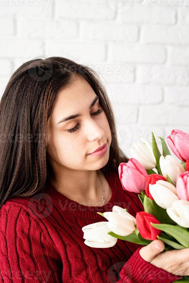 schöne brünette frau, die frische tulpen riecht foto