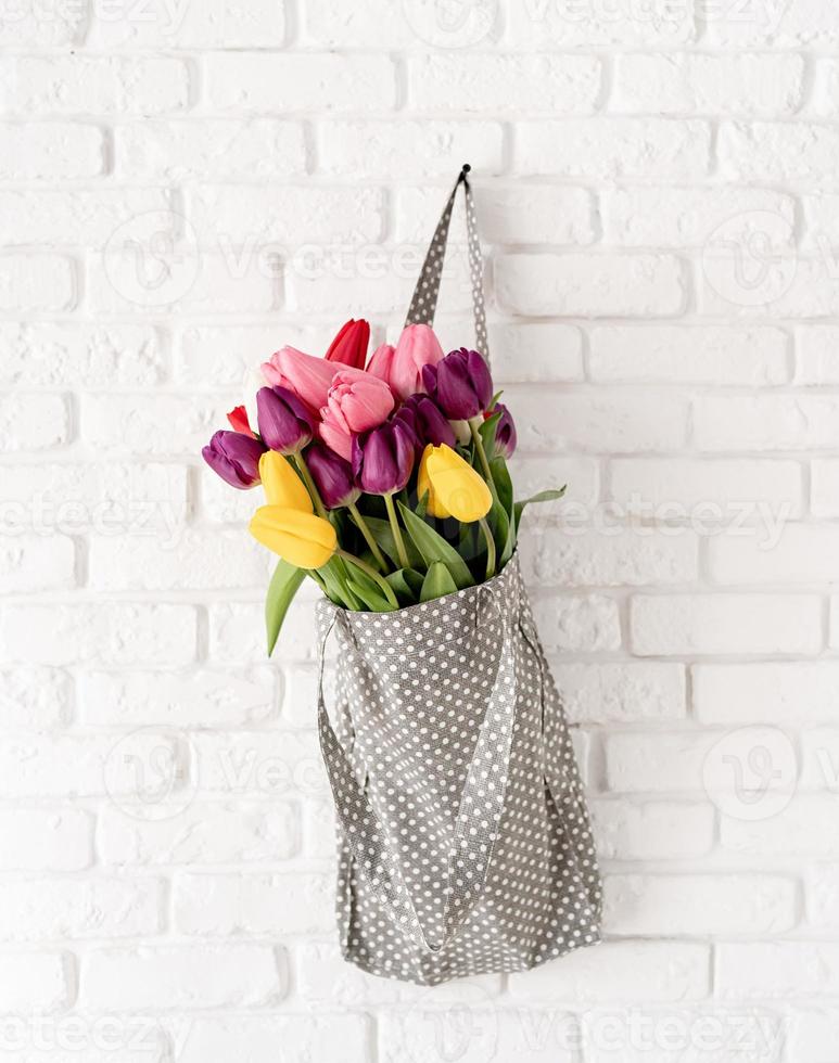 graue gepunktete Stofftasche voller bunter Tulpen foto