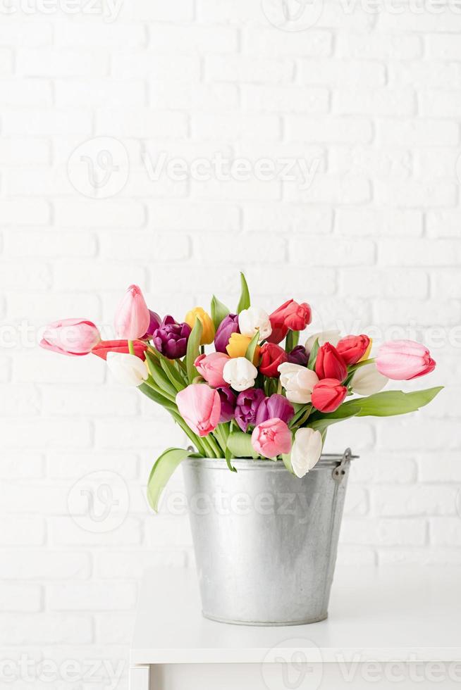 Eimer Tulpenblumen über weißem Backsteinmauerhintergrund foto