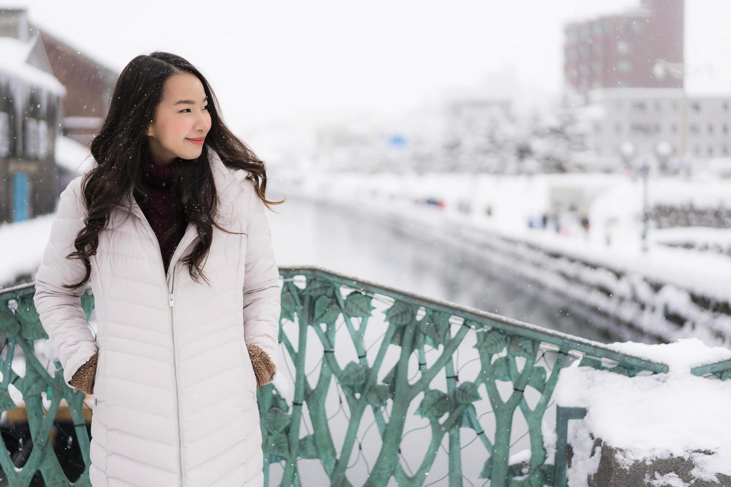 asiatische Frau, die glücklich für Reisen in der Schneewintersaison lächelt foto