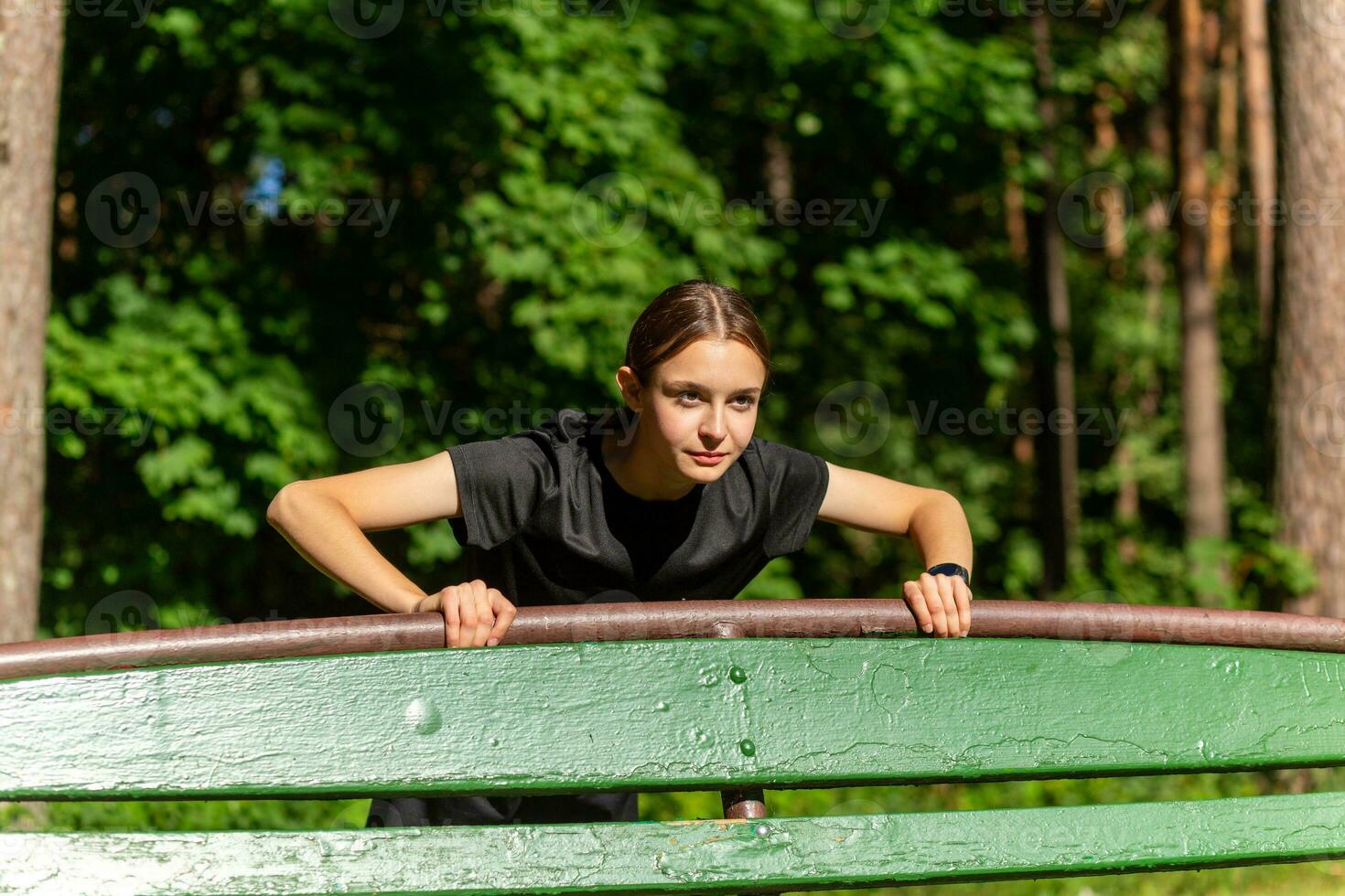 schön jung sportlich Frau im schwarz T-Shirt, schwarz kurze Hose und Rosa Sportschuhe Erwärmen oben ausüben Trizeps und Truhe foto